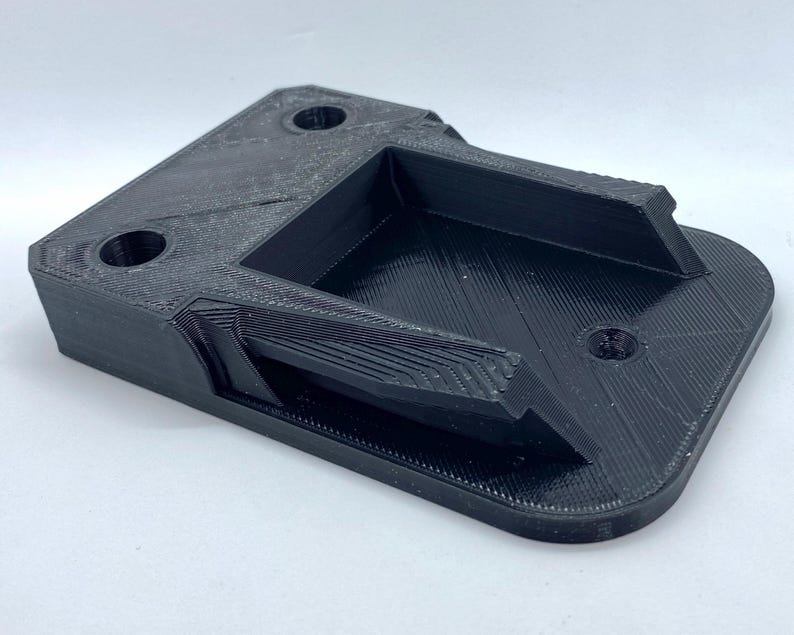 K&ouml;nnte beinhalten: Ein schwarzer 3D-gedruckter Kunststoffhalter mit einer rechteckigen &Ouml;ffnung und zwei runden L&ouml;chern.