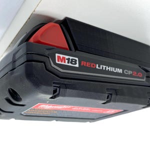 May include: A black and red Milwaukee M18 REDLITHIUM CP2.0 battery.