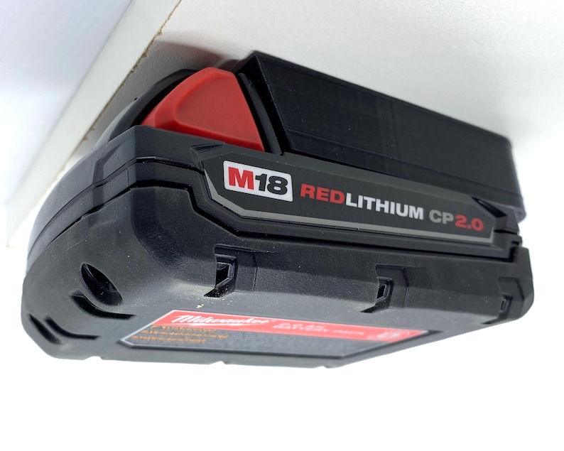 May include: A black and red Milwaukee M18 REDLITHIUM CP2.0 battery.