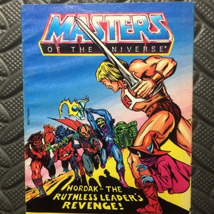 May include: A vintage Masters of the Universe comic book cover featuring He-Man battling Skeletor and his minions. The cover features bright colours and dynamic action poses. The text on the cover reads "Masters of the Universe" and "Hordak - The Ruthless Leader's Revenge!"