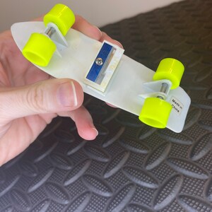 May include: A white skateboard pencil sharpener with yellow wheels. The sharpener has a blue blade and says "Made in China" on the bottom.