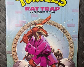 May include: A vintage "Teenage Mutant Ninja Turtles" comic book titled "Rat Trap: An Adventure to Color." The cover features a menacing rat character in a purple robe, holding a weapon, with robotic figures in the foreground. The title is in yellow.