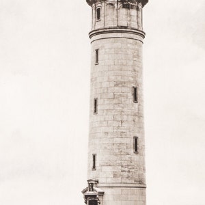 May include: A tall, white stone lighthouse with multiple windows. The lighthouse is against a cloudy sky.