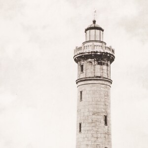May include: A tall, stone lighthouse with a white, cloudy sky in the background.
