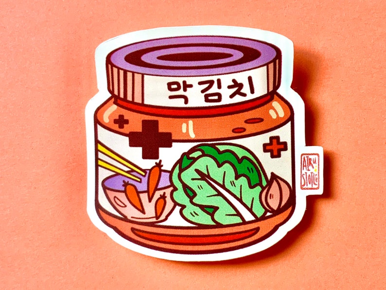Pu&ograve; includere: Un'illustrazione di cartone animato di un barattolo di kimchi, un alimento fermentato tradizionale coreano. Il barattolo &egrave; etichettato "Kimchi" in coreano e ha un coperchio viola. All'interno del barattolo ci sono illustrazioni di cavolo, aglio, carote e bacchette.