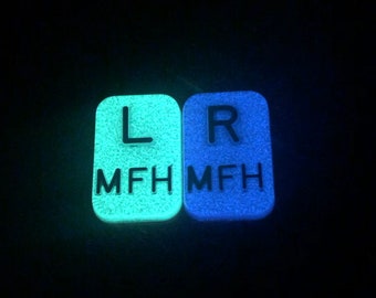 May include: Two glow-in-the-dark plastic squares with the letters "L" and "R" and the text "MFH" printed on them.