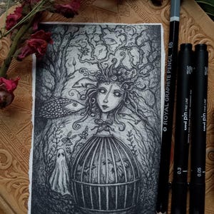 May include: A black and white illustration of a woman with intricate hair and a cage, surrounded by a forest. A ghost figure is present. A pencil and two black pens are next to the illustration. The text on the pencil reads "ROYAL GRAPHITE PENCIL 6B".