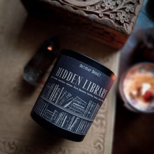 May include: A white ceramic mug with a black handle and the text "But First, Coffee" in a black, handwritten-style font. The mug is on a white surface.