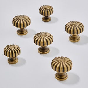 Könnte beinhalten: Sechs antike Messing-Schrankknöpfe mit geriffeltem Design. Die Knöpfe haben eine runde Basis und eine erhabene, geriffelte Oberseite.