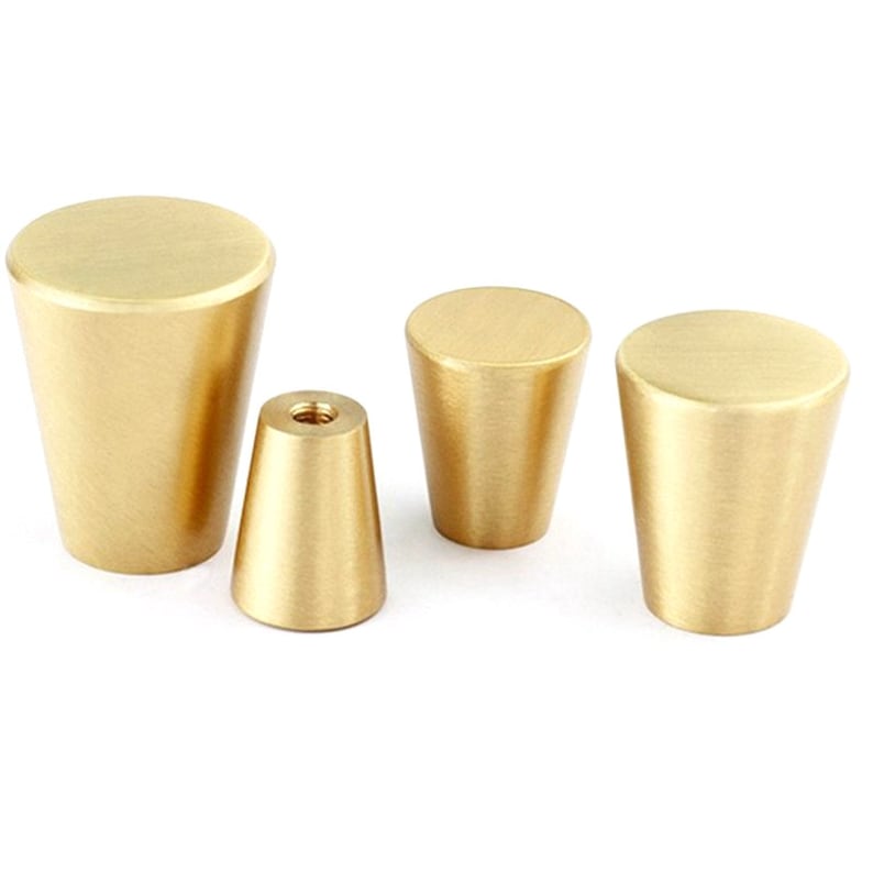 May include: Four gold-toned metal cabinet knobs in different sizes. The knobs are all cone-shaped with a smooth, brushed finish.
