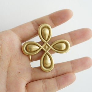 May include: A gold-colored metal flower-shaped pendant with a geometric design in the center.