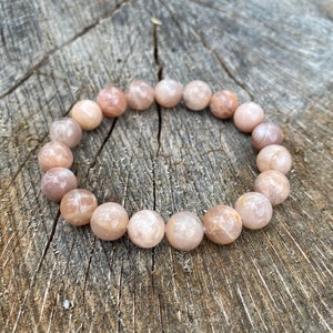 May include: A sunstone bracelet with light pink and white beads. The bracelet is made of natural stones and is approximately 18 cm in length.