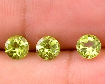 May include: Three round, faceted, green peridot gemstones.