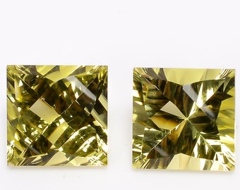 May include: Two square-shaped, faceted, yellow gemstones with a golden hue. The gemstones are cut in a square shape with a pointed top and bottom.