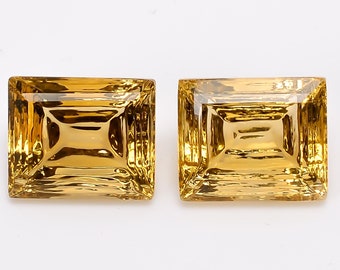 May include: Two golden yellow rectangular gemstones with a faceted cut.