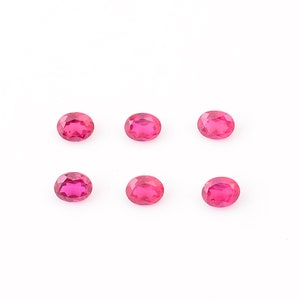 Puede incluir: Seis piedras preciosas ovaladas de color rosa brillante sobre un fondo blanco.