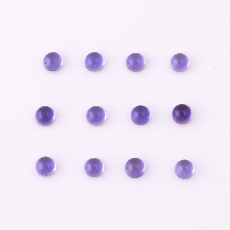 May include: Twelve round, purple gemstones arranged in three rows of four on a white background.