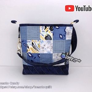 Peut inclure: Un sac fourre-tout en tissu patchwork bleu et blanc avec une longue bandoulière. Le sac a une fermeture éclair et une petite étiquette en tissu bleu et blanc qui dit "Tomato candy".