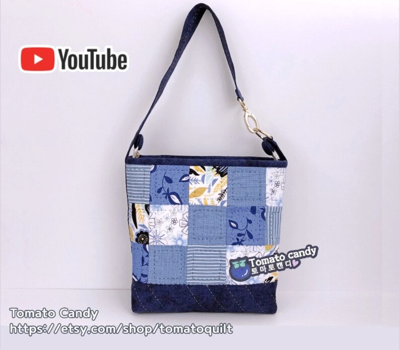 Pode incluir: Uma bolsa tote de patchwork azul e branco com uma al&ccedil;a de brim e um fecho dourado. A bolsa tem um padr&atilde;o floral e o texto "Tomato candy" em coreano.