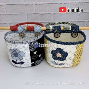 May include: Three quilted fabric hanging baskets with different patterns and colors. The baskets are made of patchwork fabric with floral designs and plaid patterns. The baskets are hanging from a wooden dowel rod. The baskets are labeled with the text "Tomato candy".
