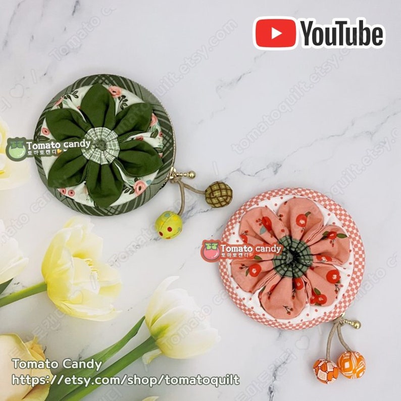 K&ouml;nnte beinhalten: Zwei runde M&uuml;nzbeutel mit floralen Stoffdesigns. Der Beutel links ist gr&uuml;n mit einer wei&szlig;en Blume und der Beutel rechts ist rosa mit einer roten Blume. Beide Beutel haben einen kleinen Quasten mit einer dekorativen Perle.