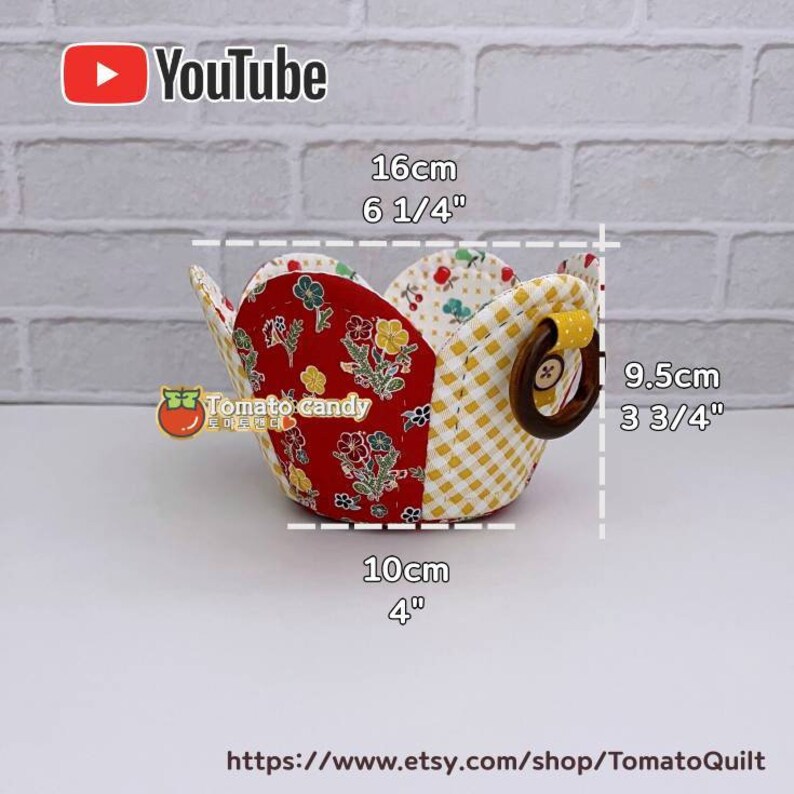 Peut inclure: Un panier en tissu rouge et jaune avec une poign&eacute;e en bois. Le panier mesure 16 cm de haut, 9,5 cm de large et 10 cm de diam&egrave;tre.