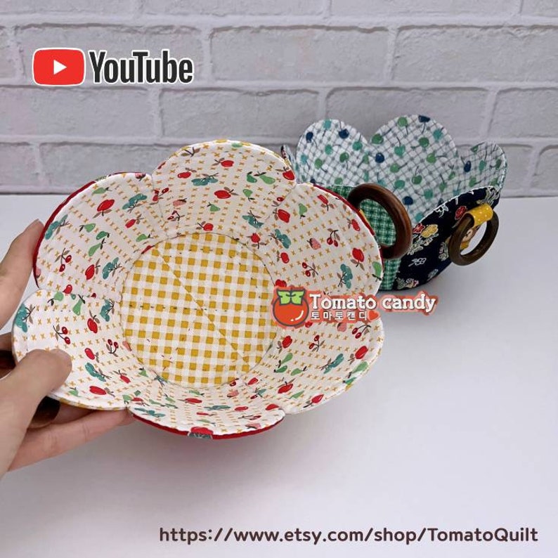Peut inclure: Deux bols en tissu en forme de fleur avec un motif &agrave; carreaux jaunes et blancs &agrave; l'int&eacute;rieur. Les bols sont faits de tissu patchwork avec un motif floral rouge, blanc et vert. Les bols ont une poign&eacute;e en bois.