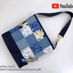Pode incluir: Uma bolsa tote de tecido patchwork azul e branco com estampa floral. A bolsa tem uma al&ccedil;a longa ajust&aacute;vel e um fecho dourado. A bolsa &eacute; feita por Tomato Candy e o site &eacute; https://etsy.com/shop/tomatoquilt.