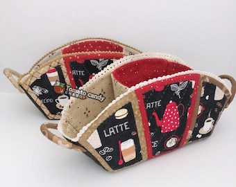 May include: Two fabric baskets with handles, featuring a black, red, and beige coffee-themed print with illustrations of teapots, coffee cups, and the word LATTE. The baskets have a quilted texture, scalloped lace trim, and red interior lining.