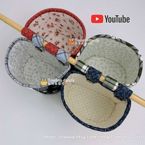 May include: Three fabric hanging baskets with different patterns. The baskets are attached to a wooden dowel rod. The baskets are lined with a white fabric with a small pattern. The baskets are made of a variety of fabrics, including plaid, floral, and geometric patterns. The baskets are labeled with the text "Tomato Candy".