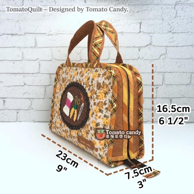 May include: A brown and yellow fabric zippered tote bag with a floral pattern and a brown and yellow plaid handle. The bag is 9 inches wide, 6 1/2 inches tall, and 3 inches deep. The bag has a small embroidered patch with a spool of thread, scissors, and needles.