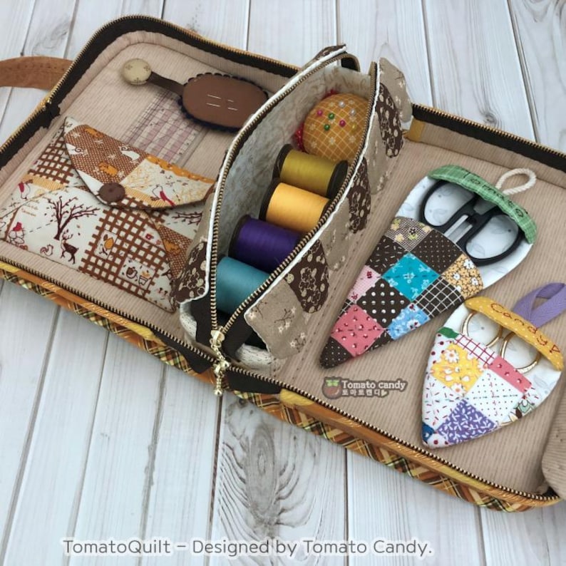 May include: A brown and beige patchwork fabric sewing kit with a zippered pouch containing spools of thread, a pincushion, and a pair of scissors. The kit also includes two separate pockets for scissors, each with a patchwork fabric design.