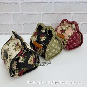May include: Three fabric pouches with floral patterns in cream, black, and pink. Each pouch has a unique design, with a contrasting border and a button closure. The text "Tomato candy" is visible on a small label on each pouch.
