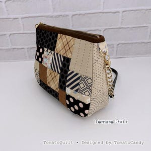 Può includere: Una borsa a mano in patchwork trapuntato con una varietà di motivi in tessuto, tra cui pois neri, quadri beige e forme geometriche. La borsa presenta una cerniera dorata, una tracolla a catena dorata e il testo TomatoQuilt Designed by TomatoCandy.