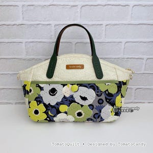 Pode incluir: Bolsa acolchoada creme com um padrão floral em tons de verde, amarelo e cinza. A bolsa tem acabamentos, alças e fecho de correr verdes. O texto "Tomato candy" e "TomatoQuilt • Designed by TomatoCandy" são visíveis.