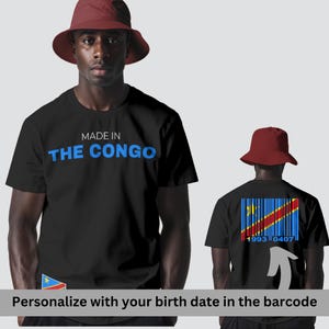 Könnte beinhalten: Schwarze T-Shirts mit dem Text "MADE IN THE CONGO" in Blau. Auf der Rückseite des Shirts befindet sich ein Barcode-Design mit der Flagge der Demokratischen Republik Kongo und den Zahlen "1993 0407". Das Bild zeigt eine Person mit einem bordeauxfarbenen Fischerhut.