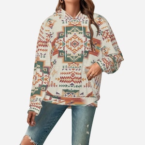 May include: Cream-coloured hoodie with a Southwestern geometric pattern in shades of green, orange, and brown. The long-sleeved sweatshirt features a front pocket and a drawstring hood. The design is repeated across the entire garment.