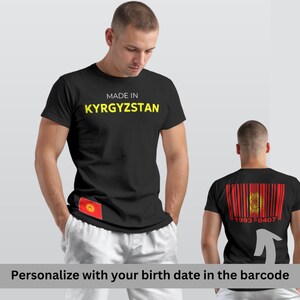 Könnte beinhalten: Schwarzes T-Shirt mit gelbem Aufdruck "MADE IN KYRGYZSTAN". Das Shirt zeigt die Flagge von Kirgisistan auf der Vorderseite und ein Barcode-Design mit der Flagge auf der Rückseite. Der Text "Personalisieren Sie mit Ihrem Geburtsdatum im Barcode" steht unten.