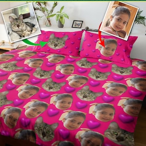 Könnte beinhalten: Rosa Bettbezug mit einem sich wiederholenden Muster aus Gesichtern und Herzen. Die Gesichter sind von einem jungen Mädchen und einer Katze. Der Text "CUSTOM FACE DUVET COVERS SEND US YOUR FAVORITE FACE PHOTOS" befindet sich oben im Bild.