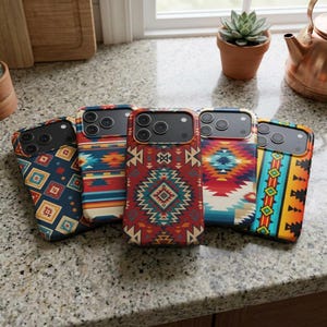 Könnte beinhalten: Fünf Smartphone-Hüllen mit farbenfrohen, geometrischen Mustern im Südweststil. Die Hüllen zeigen Designs in Rot-, Blau-, Orange- und Gelbtönen. Die Hüllen sind auf einer gesprenkelten Arbeitsplatte angeordnet und zeigen die Vielfalt der Designs.