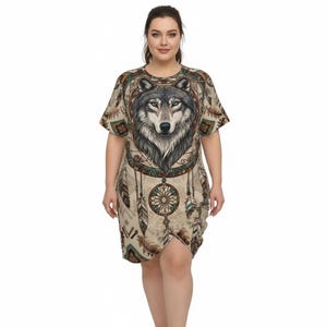 May include: A beige, short-sleeved dress featuring a detailed wolf portrait with blue eyes. The dress incorporates a dreamcatcher design with feathers and geometric patterns. The overall design has a Native American theme.