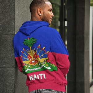 May include: A blue and red hoodie with the Haitian flag and the word "HAITI" printed on the back.