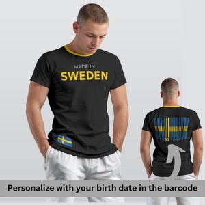 Op de afbeelding: Zwart T-shirt met gele bies en de tekst "MADE IN SWEDEN" in het geel. Het shirt heeft de Zweedse vlag op de voorkant en een barcode-ontwerp met de vlag op de achterkant. Het shirt heeft een ronde hals.