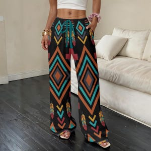 May include: Black palazzo pants with a vibrant geometric pattern in teal, orange, and yellow. The design features diamond shapes and feather motifs. The pants have a drawstring waist and pockets.