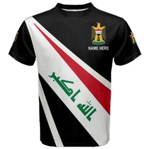 Può includere: Maglietta nera con un design diagonale che presenta la bandiera dell'Iraq. La bandiera ha i colori rosso, bianco, nero e verde. Il testo arabo "Allahu Akbar" è visibile sulla bandiera. Le parole "NAME HERE" sono stampate sulla maglietta.