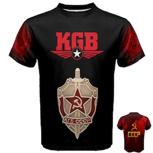 Peut inclure: T-shirt noir avec le texte rouge "KGB" au-dessus d'un écusson. L'écusson présente une étoile, un marteau et une faucille, et le texte "KGB CCCP". Les manches ont un motif rouge et noir.