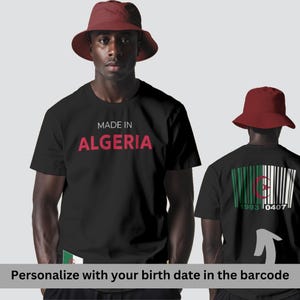 以下が含まれることがあります： 「MADE IN ALGERIA」の赤い文字が入った黒いTシャツ。Tシャツの背面には、アルジェリアの国旗と「1993 0407」の文字が入ったバーコードのデザインが施されています。どちらのモデルも赤いバケットハットを着用しています。