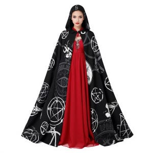 May include: A black hooded cloak with white occult symbols and patterns. The cloak is worn over a long red dress. The hood has a matching design and a small emblem. The cloak is a dramatic, flowing garment.