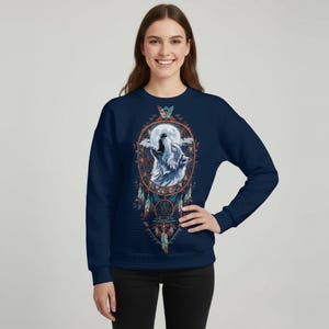 May include: Navy blue sweatshirt featuring a detailed graphic of a howling wolf inside a dreamcatcher, with a full moon in the background. The design incorporates feathers and geometric patterns in shades of blue, orange, and teal.