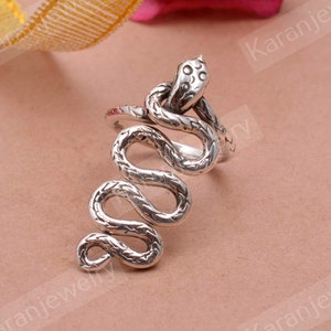 Puede incluir: Anillo de serpiente de plata con un diseño texturizado detallado. La serpiente está enroscada y la cabeza está levantada.